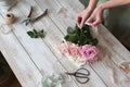 Partial view of the florist making a bouquet of flowers in a light workshop on a wooden surface. Royalty Free Stock Photo