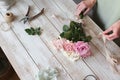 Partial view of the florist making a bouquet of flowers in a light workshop on a wooden surface. Royalty Free Stock Photo