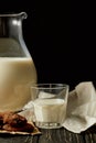 partial view of fresh milk in jug and glass, chocolate cookies and sackcloth on black background Royalty Free Stock Photo