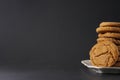 Partial view of a gingerbread cookie leaning against a stack of cookies on a white plate with a black background and copy space Royalty Free Stock Photo