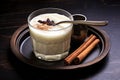 partial view of a glass of rice pudding drink and a steel spoon