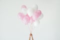 partial view of hands holding bunch of pink and white balloons