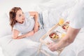 partial view of man brought breakfast in bed for smiling girlfriend