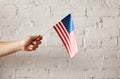 partial view of man holding american flagpole against white brick wall Royalty Free Stock Photo