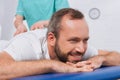 partial view of massage therapist doing massage to smiling patient on massage table Royalty Free Stock Photo
