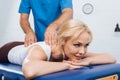 partial view of massage therapist doing massage to smiling woman Royalty Free Stock Photo