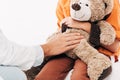 View of pediatrist in white coat and kid with teddy bear isolated on white