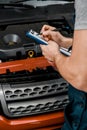 partial view of repairman with notepad examining car