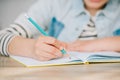 View of schoolkid writing in copy book while doing homework