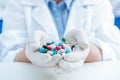 Partial view of scientist in protective gloves holding pills in hands