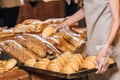 partial view of shop assistant arranging loafs of bread