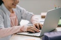 View of smiling schoolkid using laptop while doing schoolwork at home