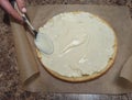 Woman confectioner smear cream on cake layer