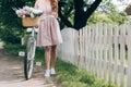partial view of woman in dress with retro bicycle with wicker basket full of flowers