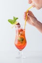 partial view of woman drinking summer cold cocktail with citrus fruits, strawberry and mint