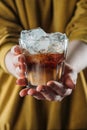 partial view of woman holding glass of cold brewed coffee with ice cubes