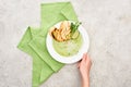 Partial view of woman holding plate with delicious creamy green vegetable soup with croutons.