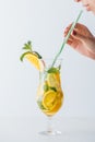 partial view of woman holding straw and summer cold cocktail with mint, lemon and orange pieces