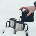 partial view of woman pouring coffee into cups in snow in winter