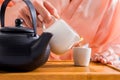 partial view of woman pouring tea into cup while having tea ceremony