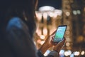 partial view of woman using smartphone with booking logo on screen night city lights