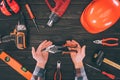 partial view of worker holding pliers with various supplies around