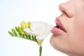 Young sensual woman holding tender white flower near lips, skincare concept