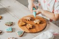 Partially blurred hands of little girl decorate gingerbread cookies with blue icing in kitchen. Child prepares cookies Royalty Free Stock Photo