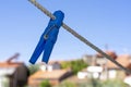 partially broken blue clothes peg stuck on the rope under blurred background