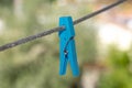partially broken blue clothes peg stuck on the rope under blurred background