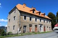 Partially destroyed abandoned large family house with broken windows and rusted rollup blinds on doors mounted on dilapidated