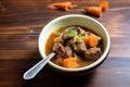 partially eaten beef stew in bowl, spoon resting beside