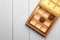 Partially empty box of chocolate candies on white wooden table, top view. Space for text Royalty Free Stock Photo