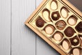 Partially empty box of chocolate candies on white wooden table, top view. Space for text Royalty Free Stock Photo