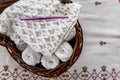 Blanket with an original embossed crochet stitch pattern, purple crochet hook and cotton balls in a brown wicker basket Royalty Free Stock Photo