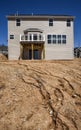 Partially finished new two-story home under construction in residential subdivision with muddy hill, vinyl siding and windows Royalty Free Stock Photo