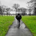 Partially grayscale shot of a young male walking in a park with green grass