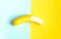 Partially peeled banana on blue yellow background.Tropic summer fruit. Royalty Free Stock Photo