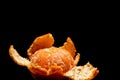 Partially peeled tangerine on a black background with blank space
