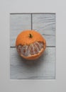 Partially peeled tangerine in frame on white wooden background. Royalty Free Stock Photo