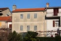 Partially renovated attached large old family house with old dilapidated facade and closed cracked wooden blinds and new roof