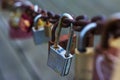 Partially rusty silver lock fastened to a rusty chain next to other locks Royalty Free Stock Photo