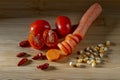 Partially sliced red cherry tomatoes and a carrot on a wooden cutting board, with red chillies and corn kernels Royalty Free Stock Photo