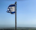 Partially torn israeli flag is waving in the wind on blue sky background