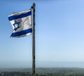 Partially torn israeli flag is waving in the wind on sky background