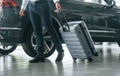 Partical view. Man in formal clothes is with luggage indoors near the car