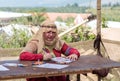 A participant in the knight festival sits at the table and paints a drawing on colored paper with colored pencils in Goren park in