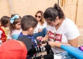 The participant of the Purim festival puts a drawing on the boy`s hand in Caesarea, Israel