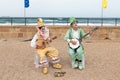 Participants of festival dressed as clowns playing stringed inst