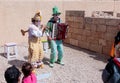 Participants of festival dressed as clowns playing stringed inst